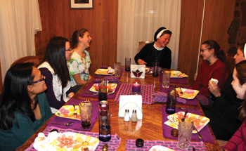 Soeur Colleen (au bout de la table) mange avec des participants pendant une retraite de discernement.