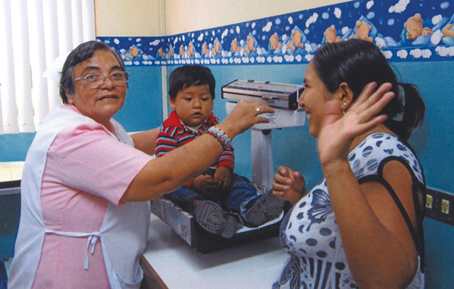 Sister Reina Lastenia, O.S.F. weighs a child at a clinic in Peru.