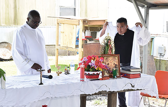 Glenmary Fathers Richard Toboso and José Carlos Miguel López vest for Mass among chicken coops and mobile homes.