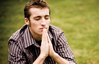 young man praying in a field