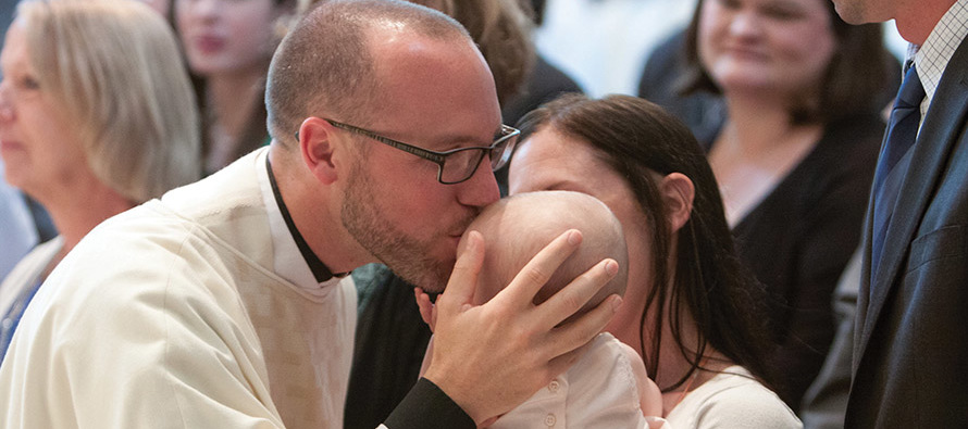 Father Paddy Gilger, S.J. gives a kiss to his goddaughter and niece, Hayden Bauer.